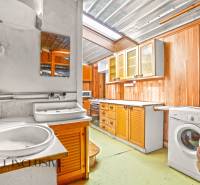 Küche in einem Einfamilienhaus mit Holzschränken, Spüle und Waschmaschine.