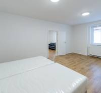 Ein Schlafzimmer in einer 3-Zimmer-Wohnung mit einem Holzboden und weißen Wänden.