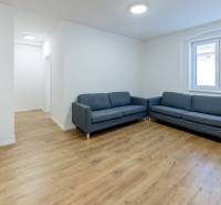 Wohnzimmer mit einem blauen Sofa und einem Boden in Holzoptik in einer 3-Zimmer-Wohnung.