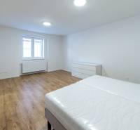 Helles Schlafzimmer mit Holzboden, Bett und Fenster in einer 3-Zimmer-Wohnung.