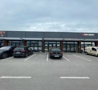 Geschäftsräume in der Brnianska-Straße in Trenčín mit einem Parkplatz vor den Geschäften.