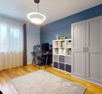 Ein Zimmer in einem Einfamilienhaus mit einem Schreibtisch, einem Regal und einem Boden mit Holzdekor.