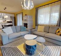 Wohnzimmer in einem Einfamilienhaus mit Holzboden, Sofas und Küche im Hintergrund.