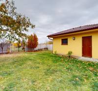 Garten bei einem Einfamilienhaus in der Ďatelinová-Straße in Iža mit einem Holzunterstand im Hof.