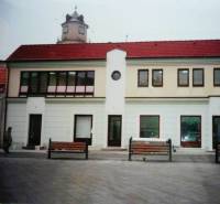 Geschäftsräume am Štúrovo námestie in Trenčín mit einem Turm im Hintergrund.