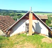 Ein Ferienhaus in Hontianske Trsťany mit traditionellem Schrägdach und einer Kulisse aus grüner Landschaft.
