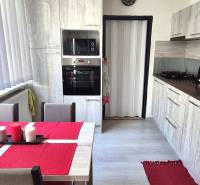 Küche mit Esstisch, weißen Jalousien und Küchenzeile in einer 2-Zimmer-Wohnung.