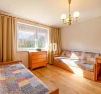 Ein Zimmer in einem Einfamilienhaus mit Betten, Holzelementen und bunten Decken.