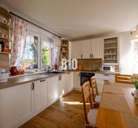 Eine Küche in einem Einfamilienhaus mit einem Boden in Holzoptik und hellen Möbeln.