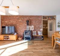 Innenraum eines Einfamilienhauses mit Ziegelwand, Ofen und Boden in Holzoptik.