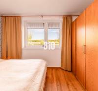 Schlafzimmer in einem Einfamilienhaus mit Holzboden und Blick aus dem Fenster.