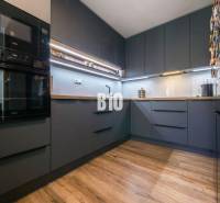 Küche in einer 3-Zimmer-Wohnung mit dunklen Schränken und einem Boden in Holzoptik.