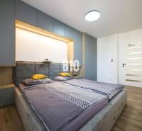 Schlafzimmer in einer 3-Zimmer-Wohnung mit Bett, Schränken und Boden in Holzdekor.