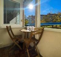 Balkon einer 3-Zimmer-Wohnung in Nitra mit Holzmöbeln und Blick ins Grüne.