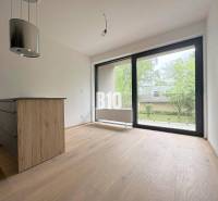 Innenraum einer 2-Zimmer-Wohnung mit Holzboden und großem Fenster mit Blick ins Grüne.