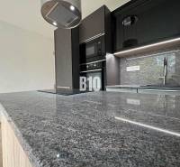 Küche in einer 2-Zimmer-Wohnung mit Marmorarbeitsplatte und moderner Ausstattung.