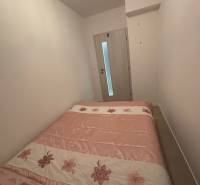 Schlafzimmer in einer 2-Zimmer-Wohnung mit einem Bett mit Blumenmotiv und hellen Wänden.