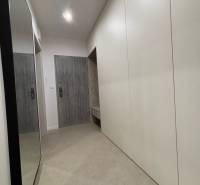 Eingangsflur einer 2-Zimmer-Wohnung mit weißen Schränken und einem Spiegel an der Wand.