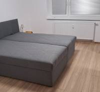 Schlafzimmer mit großem Bett und Holzboden in einer 2-Zimmer-Wohnung.