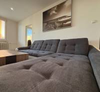 Ein helles Wohnzimmer mit einem bequemen Sofa und einem großen Fenster in einer 3-Zimmer-Wohnung.