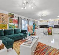 Ein buntes Wohnzimmer in einem Einfamilienhaus mit einem Sofa, einem Sessel und Kunst an den Wänden.