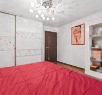 Schlafzimmer eines Einfamilienhauses mit rotem Bett, Holzboden und Kleiderschrank.