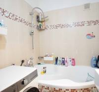 Badezimmer in einer 3-Zimmer-Wohnung mit Badewanne, Fliesen und Waschmaschine.