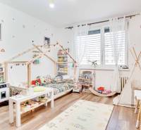 Kinderzimmer mit Pastelldekorationen, Holzboden und Spielzeug in einer 3-Zimmer-Wohnung.