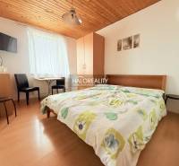 Ein Hotelzimmer mit einem Doppelbett, einem Fernseher, einem Tisch und einem Boden in Holzoptik.