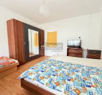 Ein Zimmer mit Bett, Schrank, Fernseher und einem Boden in Holzoptik, typisch für Hotels und Pensionen.