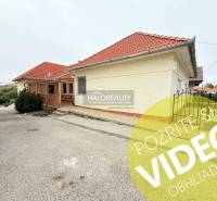 Das Äußere des Hotels und der Pension in Podhájska mit Terrasse, rotem Dach und grünen Sträuchern.