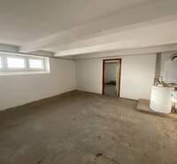 Ein leerer Raum in einem Einfamilienhaus mit Fenstern und einem Heizkessel.