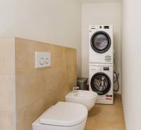 Badezimmer in einem Einfamilienhaus mit Waschmaschine, Trockner, Bidet und Toilette.