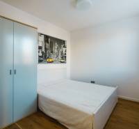 Ein Schlafzimmer in einem Einfamilienhaus mit einem einfachen Bett, einem Schrank und einem Boden mit Holzdekor.