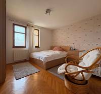Ein Zimmer mit Bett und Sessel in einer Wohnung mit 5 oder mehr Zimmern. Boden mit Holzdekor.