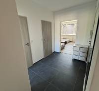 Eingangsflur in einer 3-Zimmer-Wohnung mit dunklen Fliesen und hellen Türen.