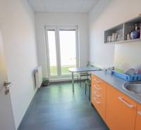 Eine Büroküche mit orangefarbenen Schränken, einem Spülbecken und einem Tisch zum Sitzen.