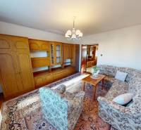 Ein Wohnzimmer in einem Einfamilienhaus mit einer Wohnwand aus Holz und einer gemusterten Sitzgarnitur.