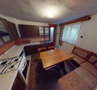 Küche in einem Einfamilienhaus mit Holzschränken, Herd und Esstisch.