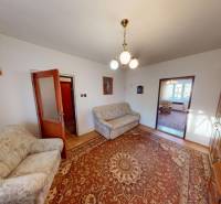 Wohnzimmer eines Einfamilienhauses mit einem bunten Teppich, Sofas und einer hölzernen Wohnwand.