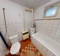 Badezimmer in einem Einfamilienhaus mit Badewanne, Toilette und Heizsystem, gefliest.