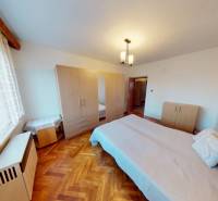 Ein Schlafzimmer in einem Einfamilienhaus mit einem Bett und einem Schrank, Boden mit Holzdekor.