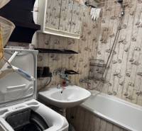 Badezimmer in einer 3-Zimmer-Wohnung mit Badewanne, Waschbecken und Waschmaschine, Tapetendekoration.
