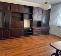 Wohnzimmer in einer 3-Zimmer-Wohnung mit Holzboden und dunklen Möbeln.