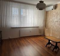 Ein Zimmer mit einem Holzboden und einem Tisch in einer 3-Zimmer-Wohnung.