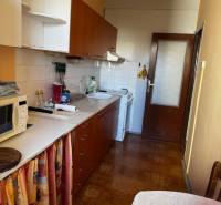 Küche in einer 3-Zimmer-Wohnung mit Holzboden, weißen Schränken, Esstisch.