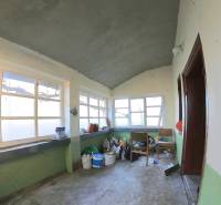 Innenraum eines Einfamilienhauses mit alten Fenstern und Betonboden.