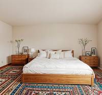 Schlafzimmer in einem Einfamilienhaus mit Bett, Nachttischen und einem bunten Teppich.