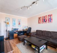 Wohnzimmer in einer 3-Zimmer-Wohnung mit Sofa, Tisch und Boden in Holzoptik.