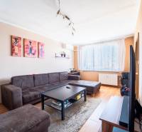 Wohnzimmer in einer 3-Zimmer-Wohnung mit Holzboden, braunen Möbeln und Dekorationen.